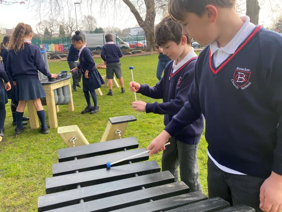 two little boys stand behind the xylophone and play with the beaters and make music