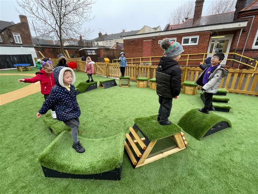A class of children playing on the movable blocks in their playground 