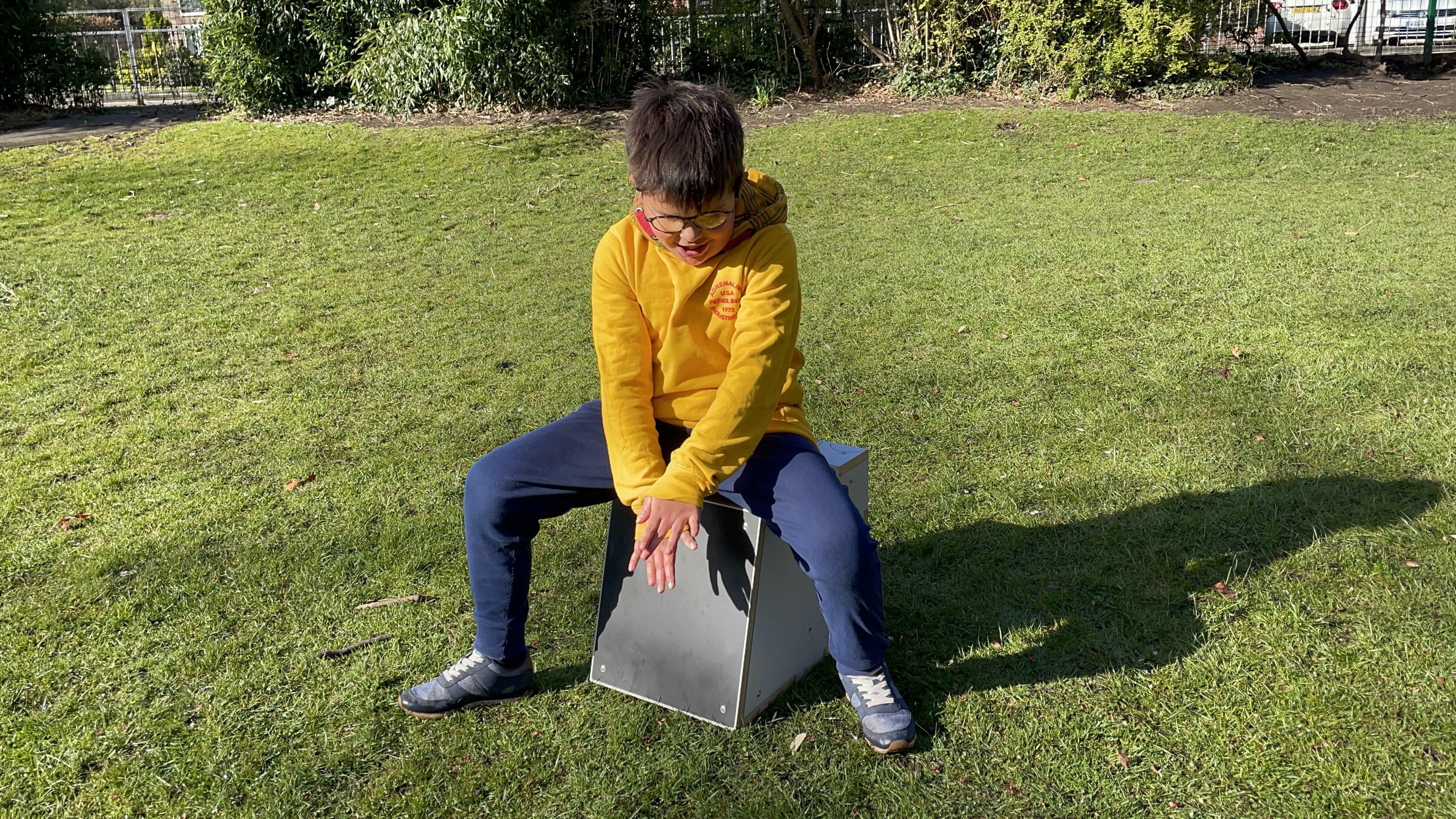 Young boy playing on a drum seat on the school playground