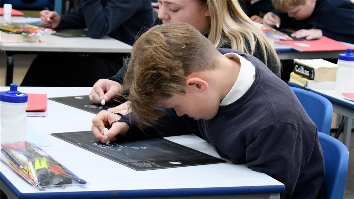 A young boy using the scribble board in his playground