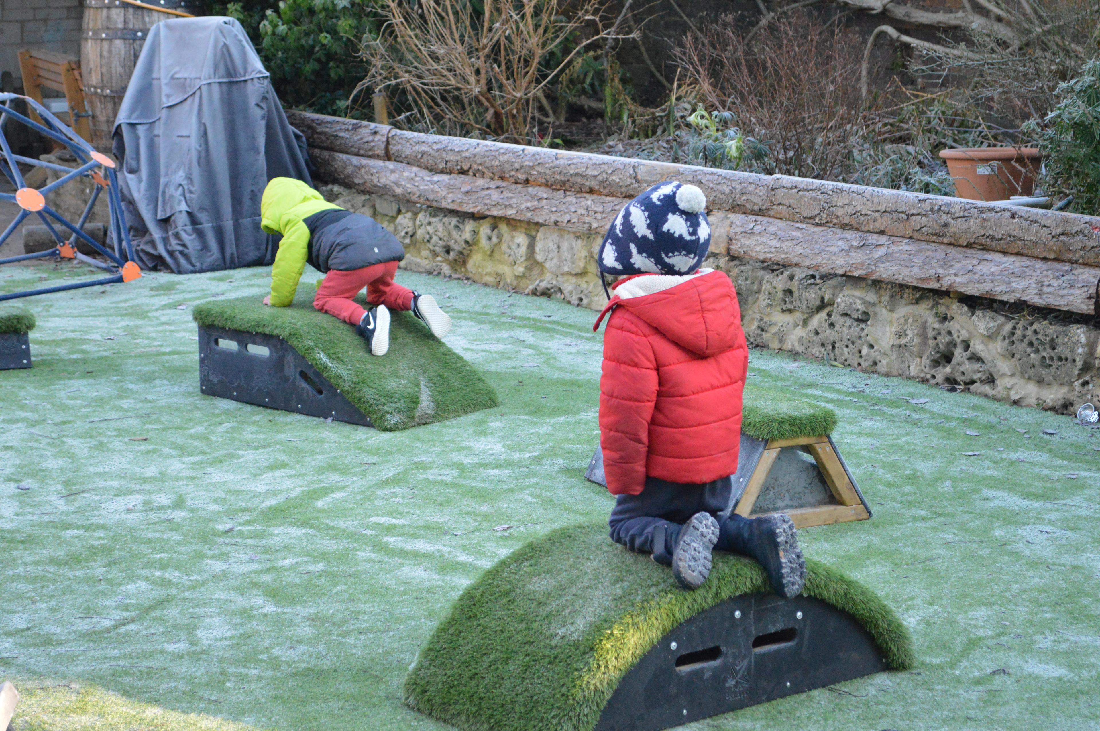 eyfs children climbing on the freely moveable playground equipment 