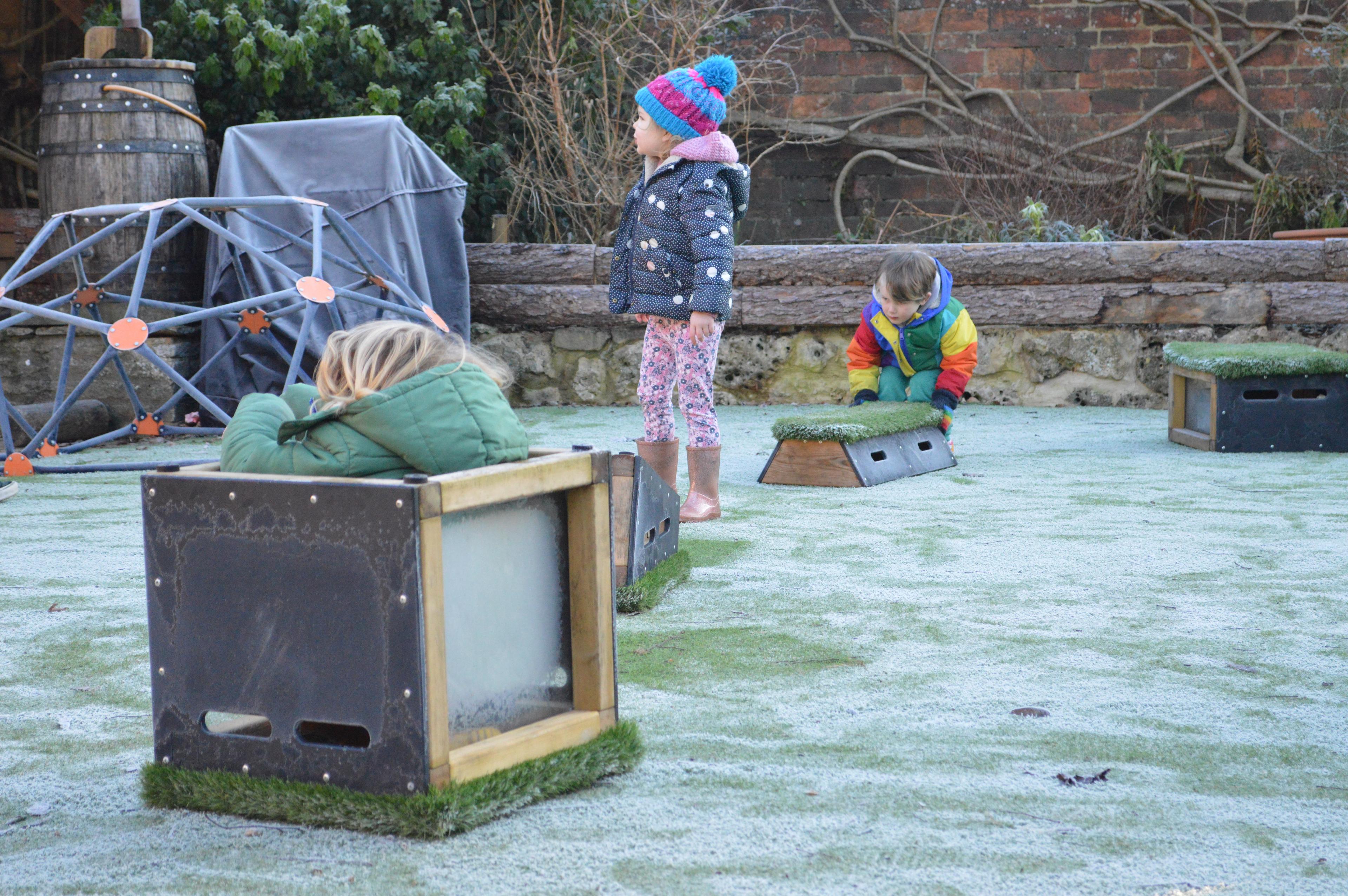 A young girl using a block in her eyfs playground as a boat 