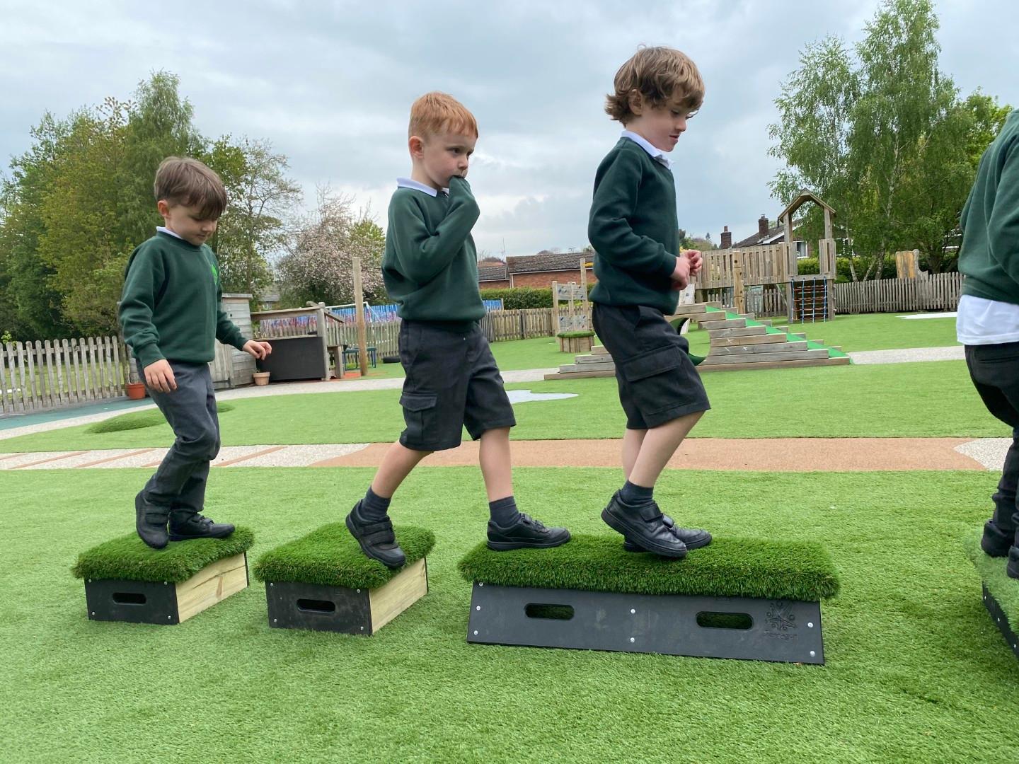School children playing on grass-topped Get Set, Go! Blocks in the playground.