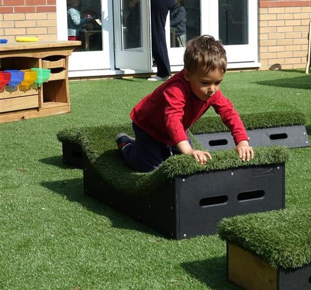 A young boy crawling across the movable blocks in his playground