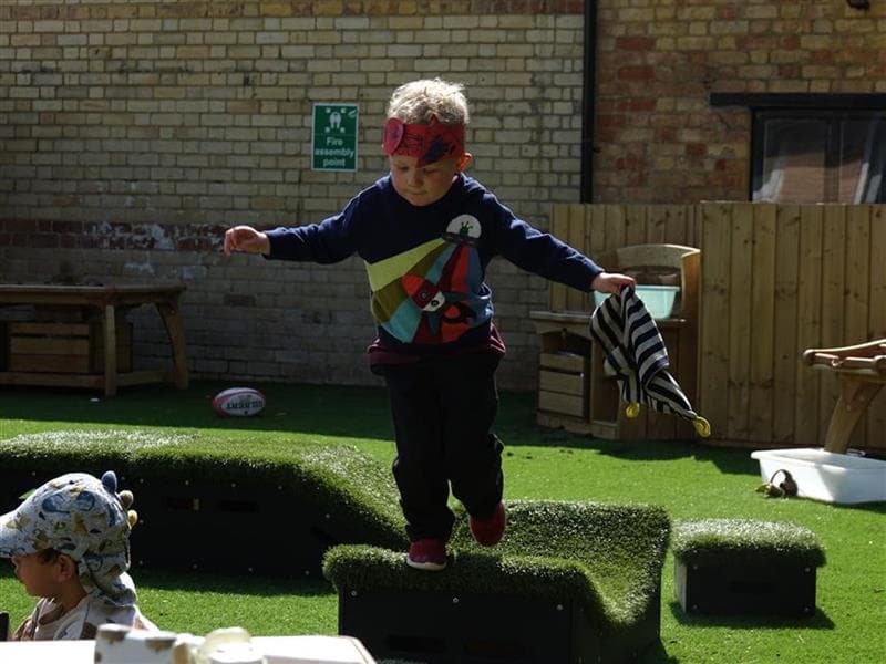 A young boy balancing on the blocks in his playground