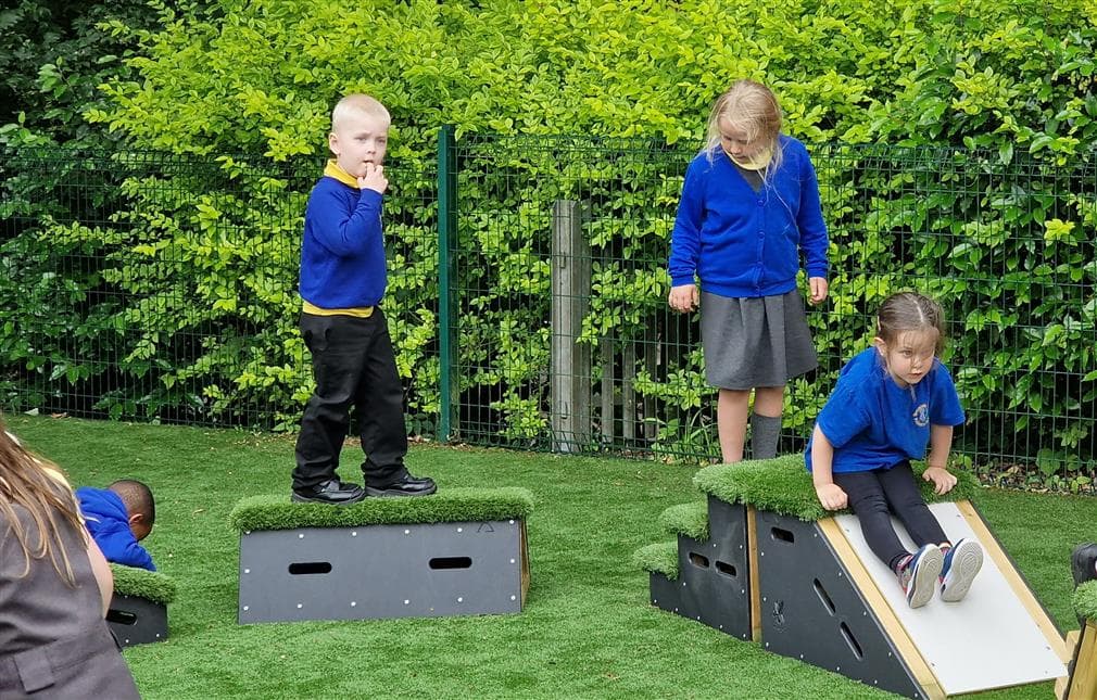 A class of children going down the slide in their playground 