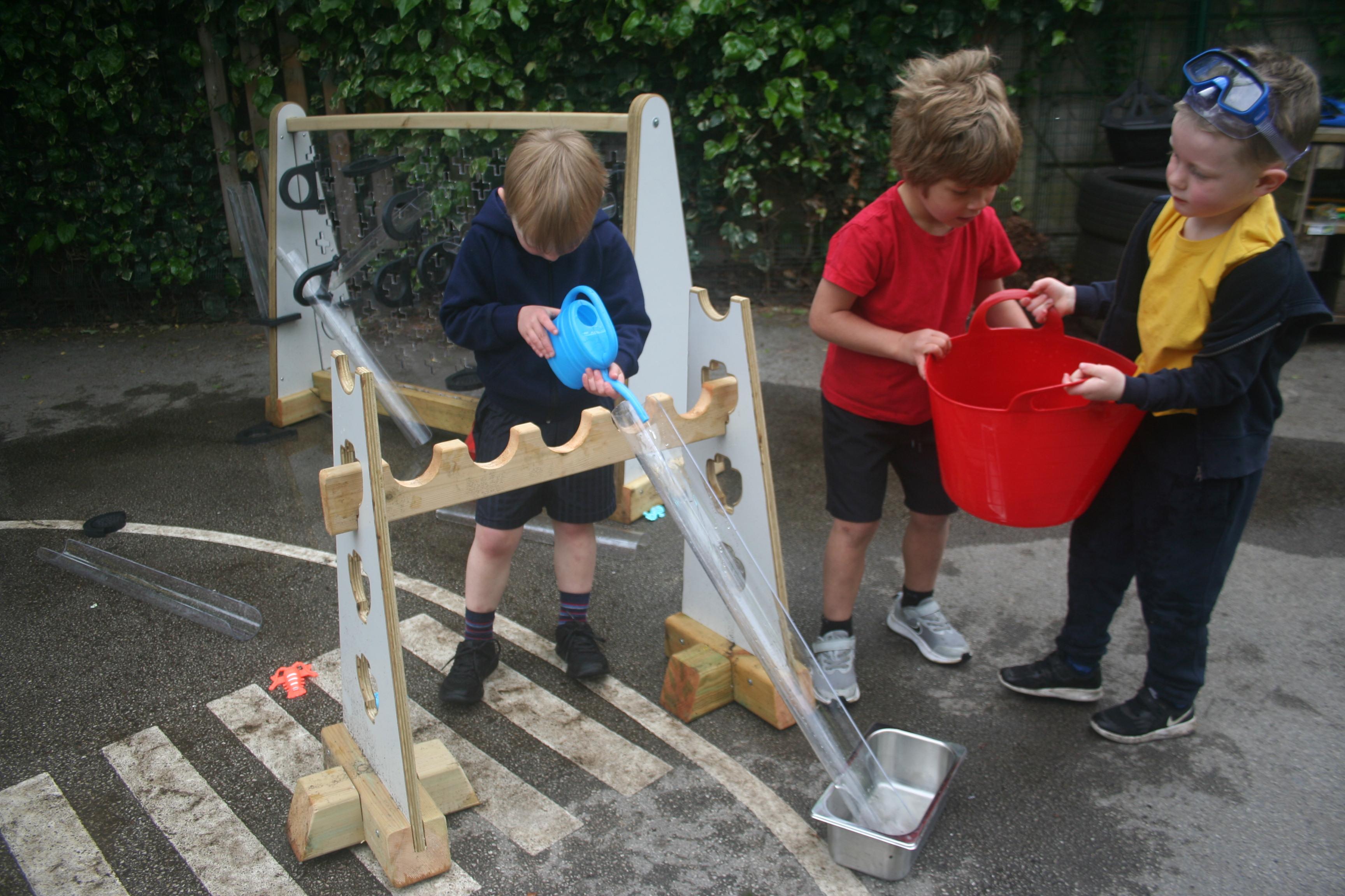 Child playing with Water Channel Stands, pouring water down the channels 