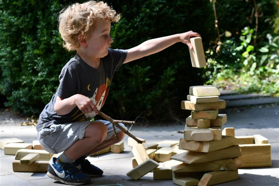 A young boy playing with the blocks form the skip