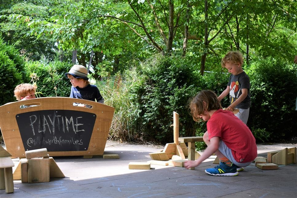 4 young boys playing with the blocks from the skip, 2 of the boys are sitting in the skip