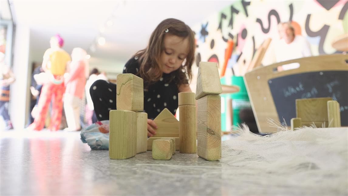 A young girl playing with the blocks from the play skip 
