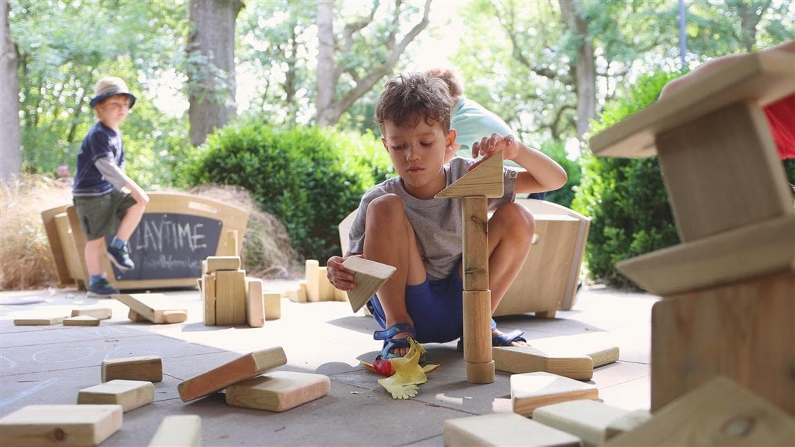 A young boy playing with the blocks from the construction play skip 