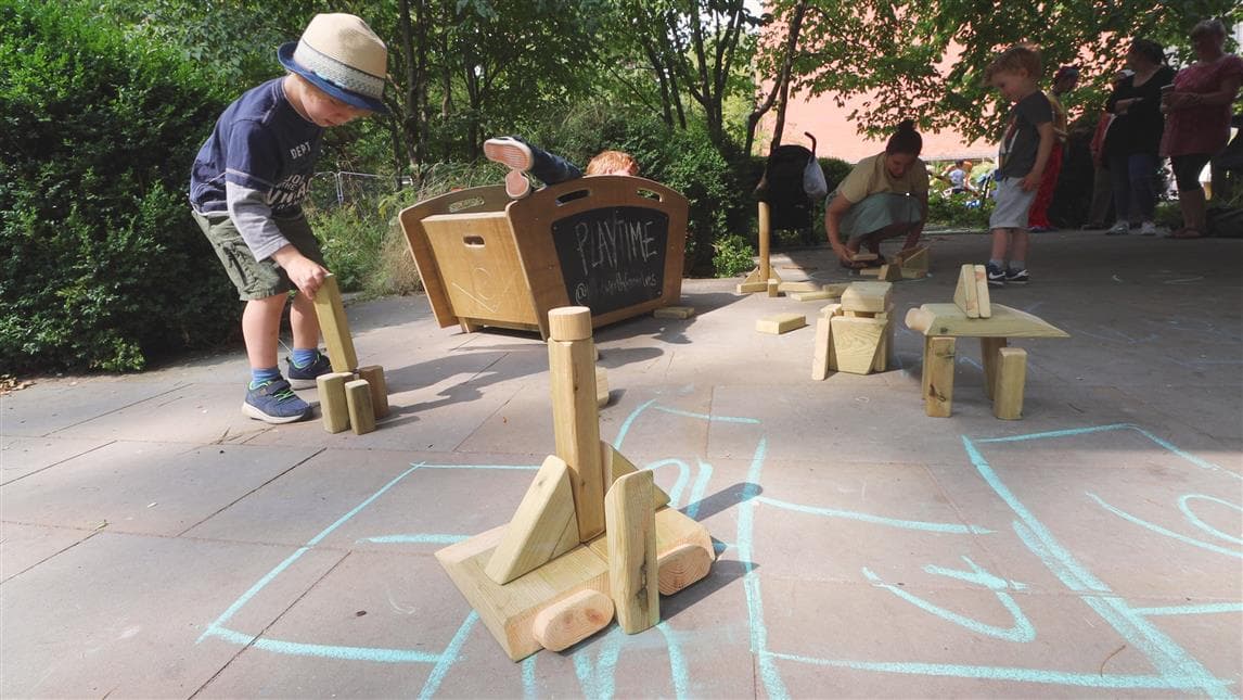 A young boy playing with the blocks in front of the construction skip