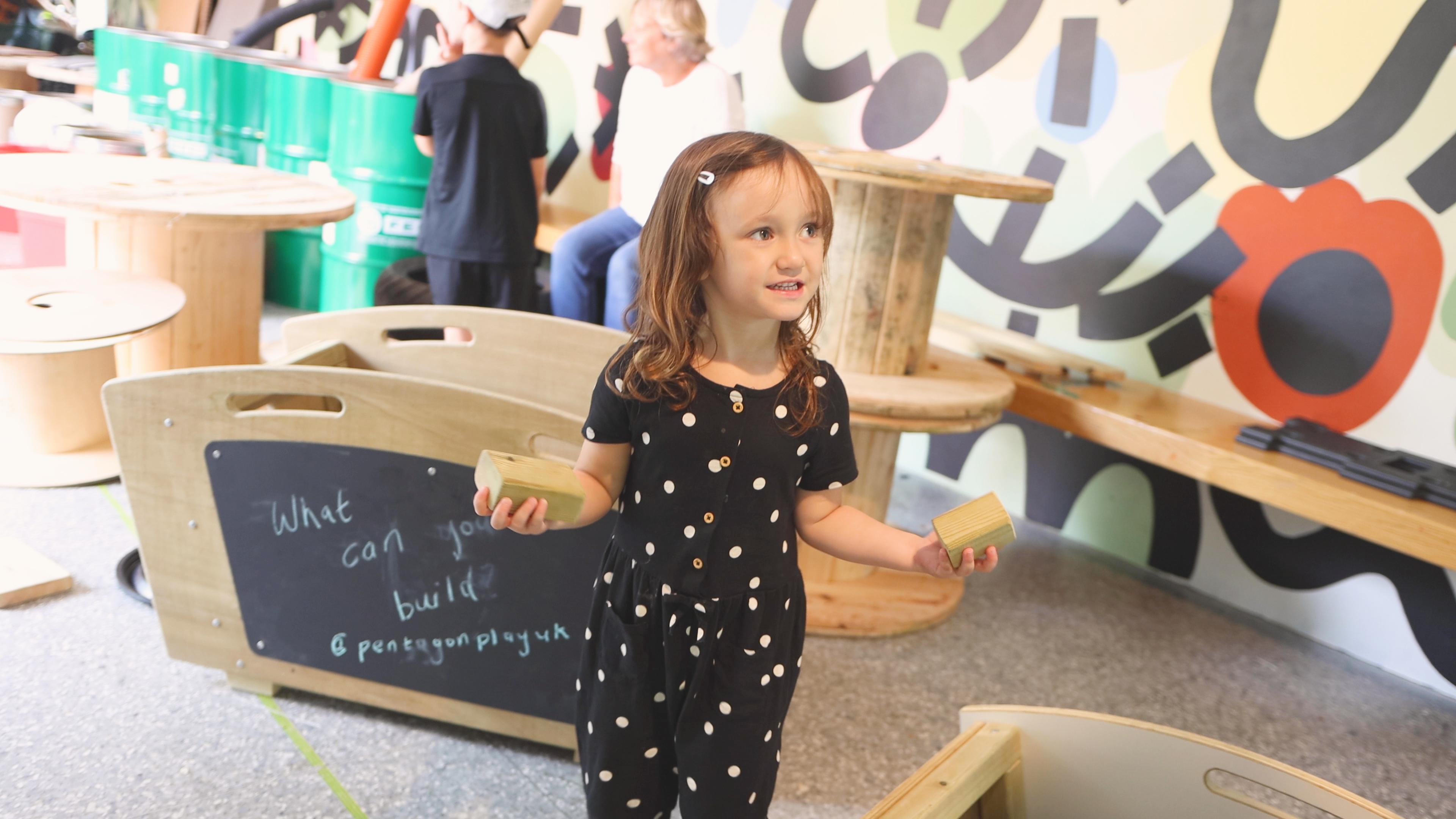 A young girl holding the blocks from the construction play skip 