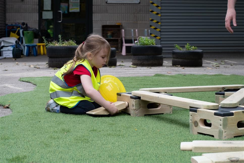 A young girl slotting in a ramp on into one of the play builder blocks