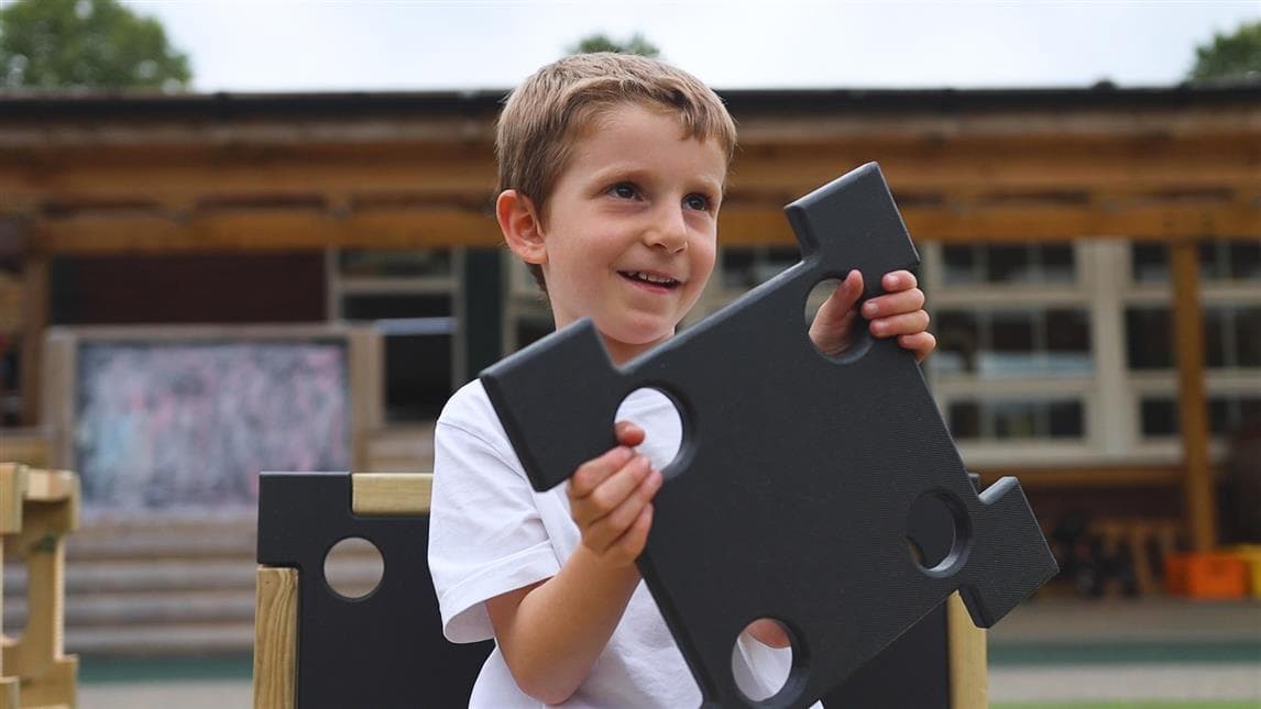 A picture of a boy holding up the cover of the play builder