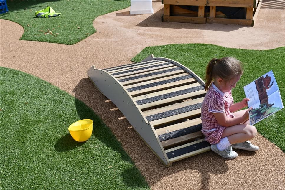 A young girl reading a story book on the play bridge 