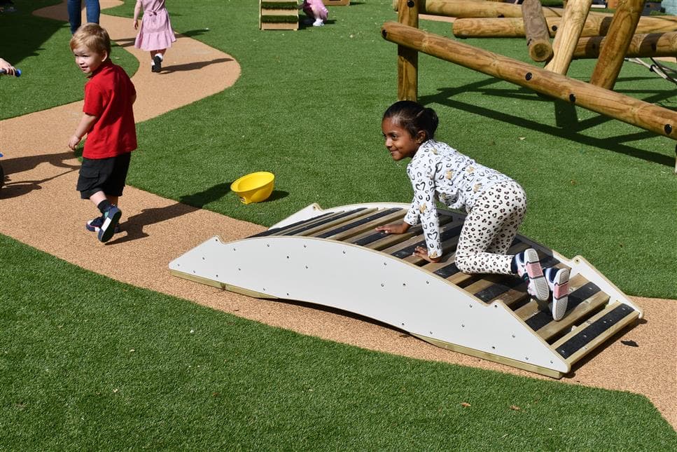 A young girl crawling across the play bridge walkway 