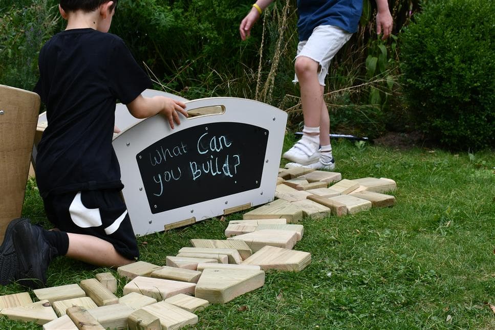 two young boys playing with the blocks on the outside of the mini skip