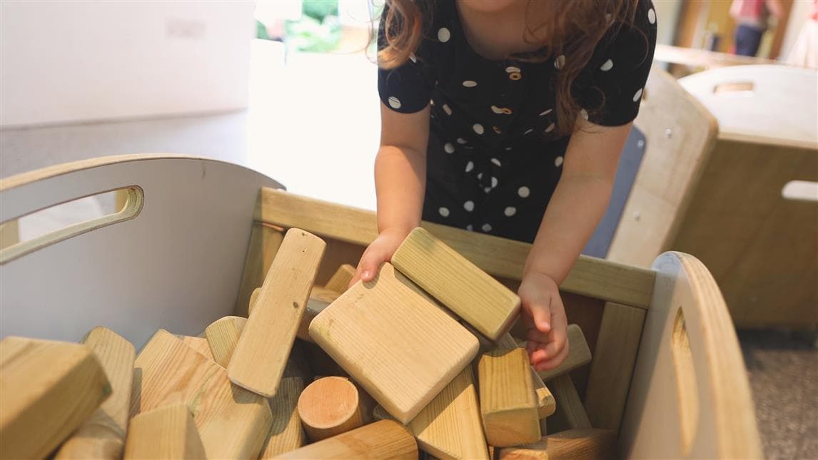A young girl putting the blocks into the mini skip