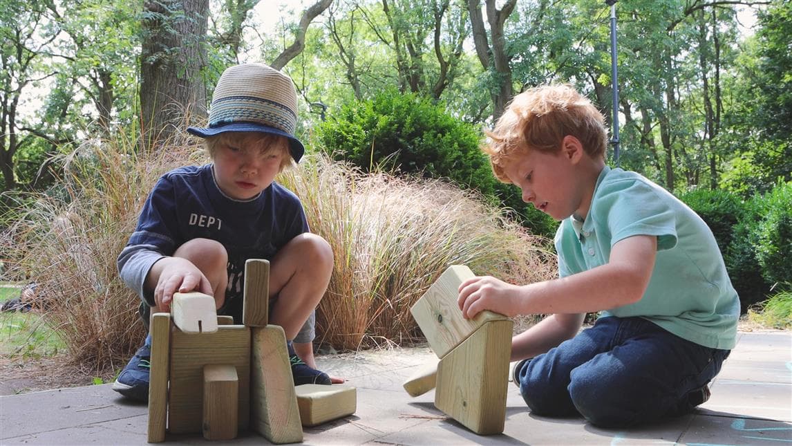 2 young boys playing with the blocks from the mini skip