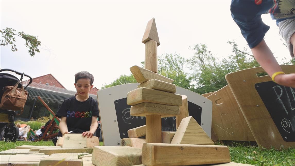 A young boy sat playing with the blocks from the mini skip