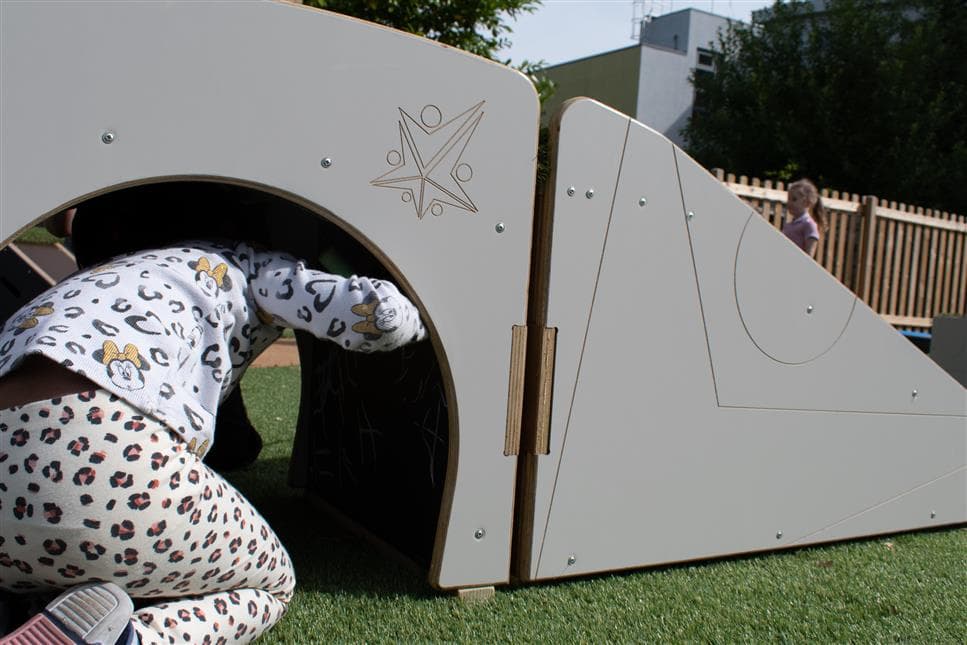 A young girl climbing through the tunnel of the up and under block