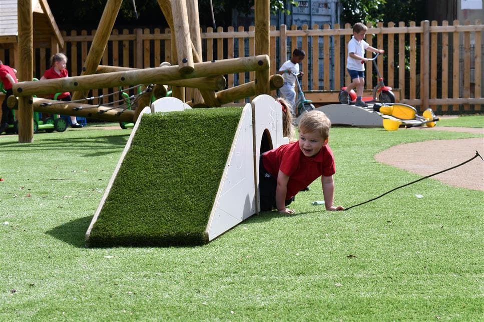 A young boy climbing out of the tunnel from the up and under bridge