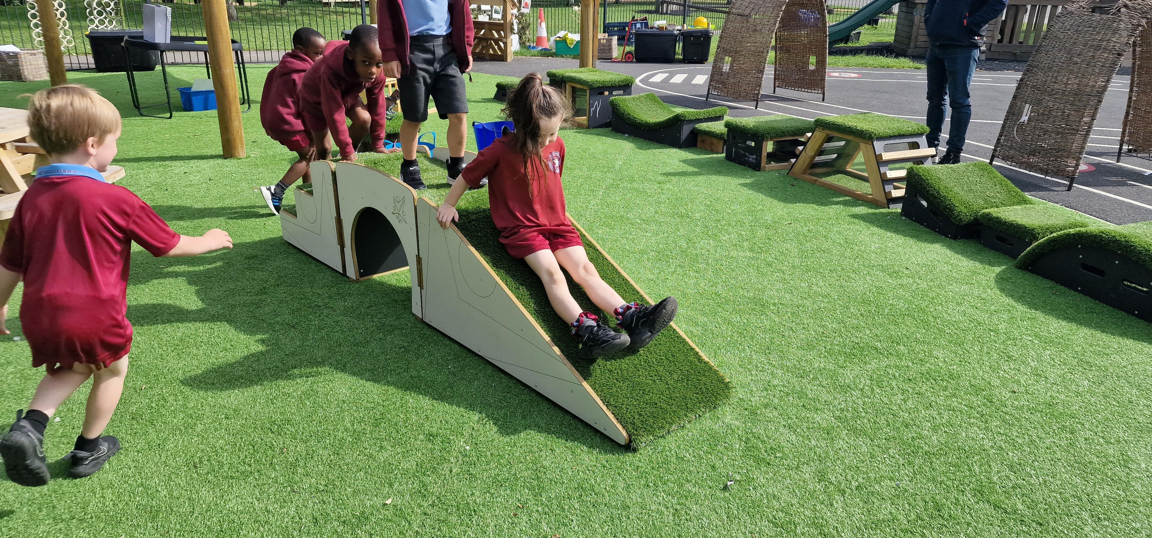 A young girl sliding down the slide on her movable blocks in her playground