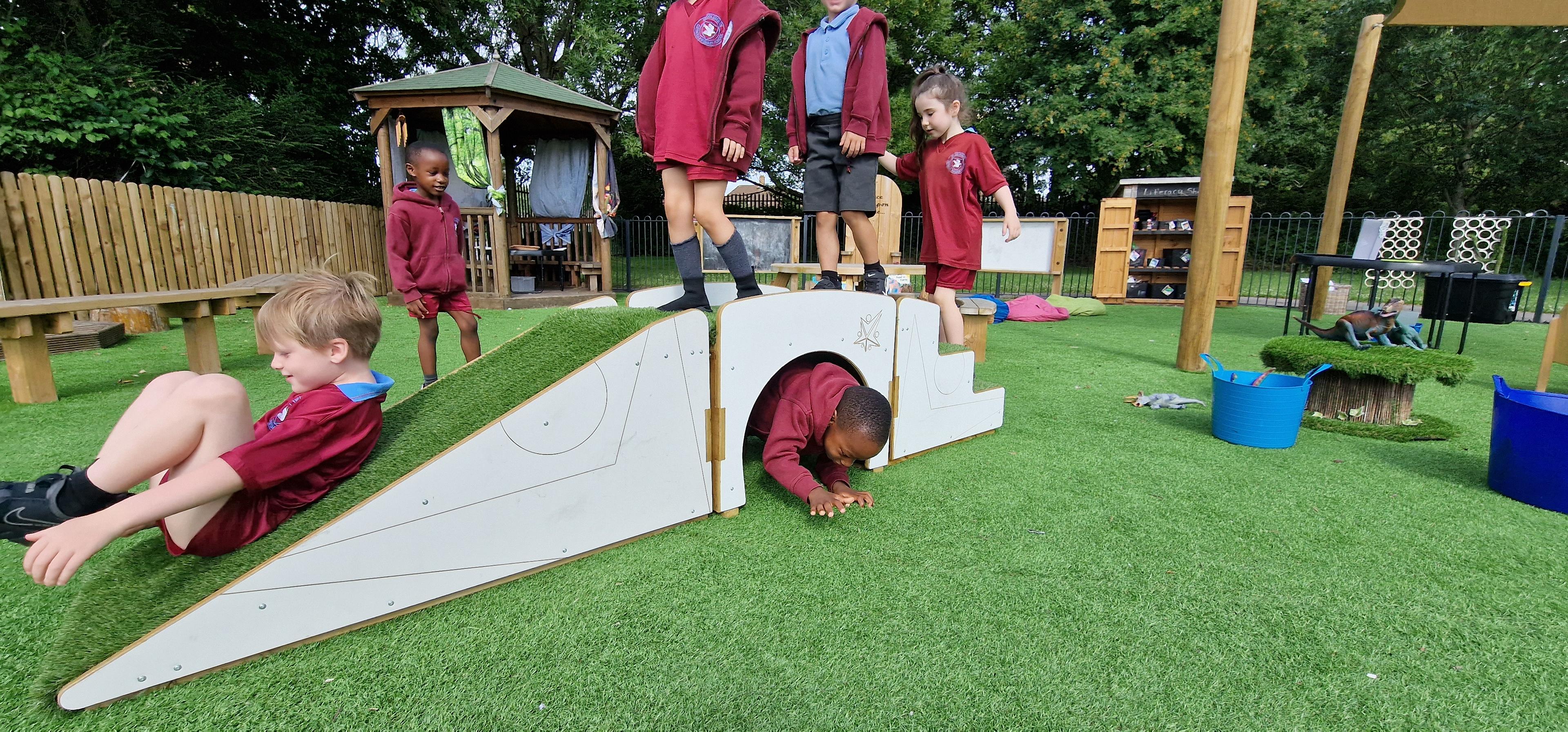 A class of children climbing over the play bridge in the playground setting