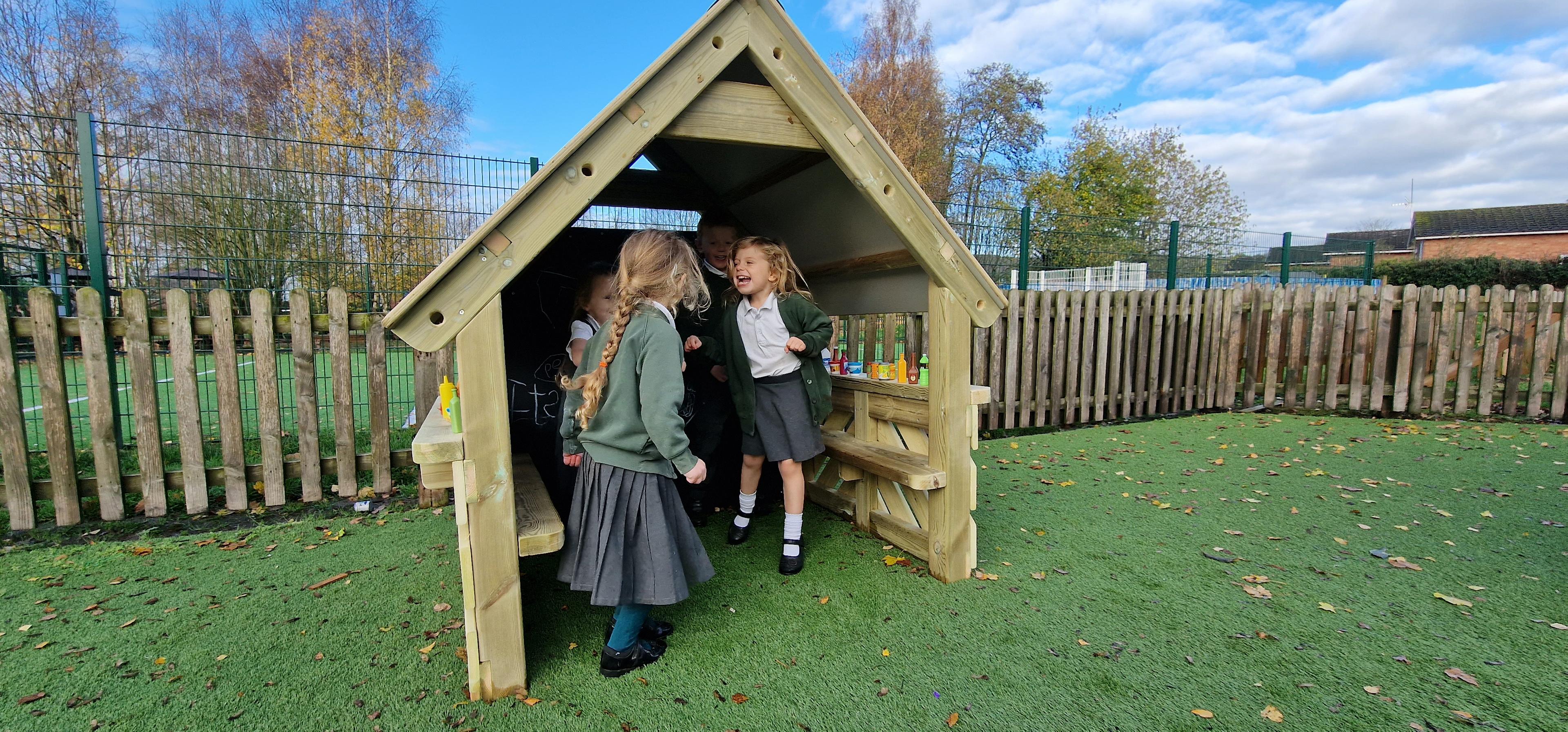 2 girls dancing in the small playhouse in their playground 