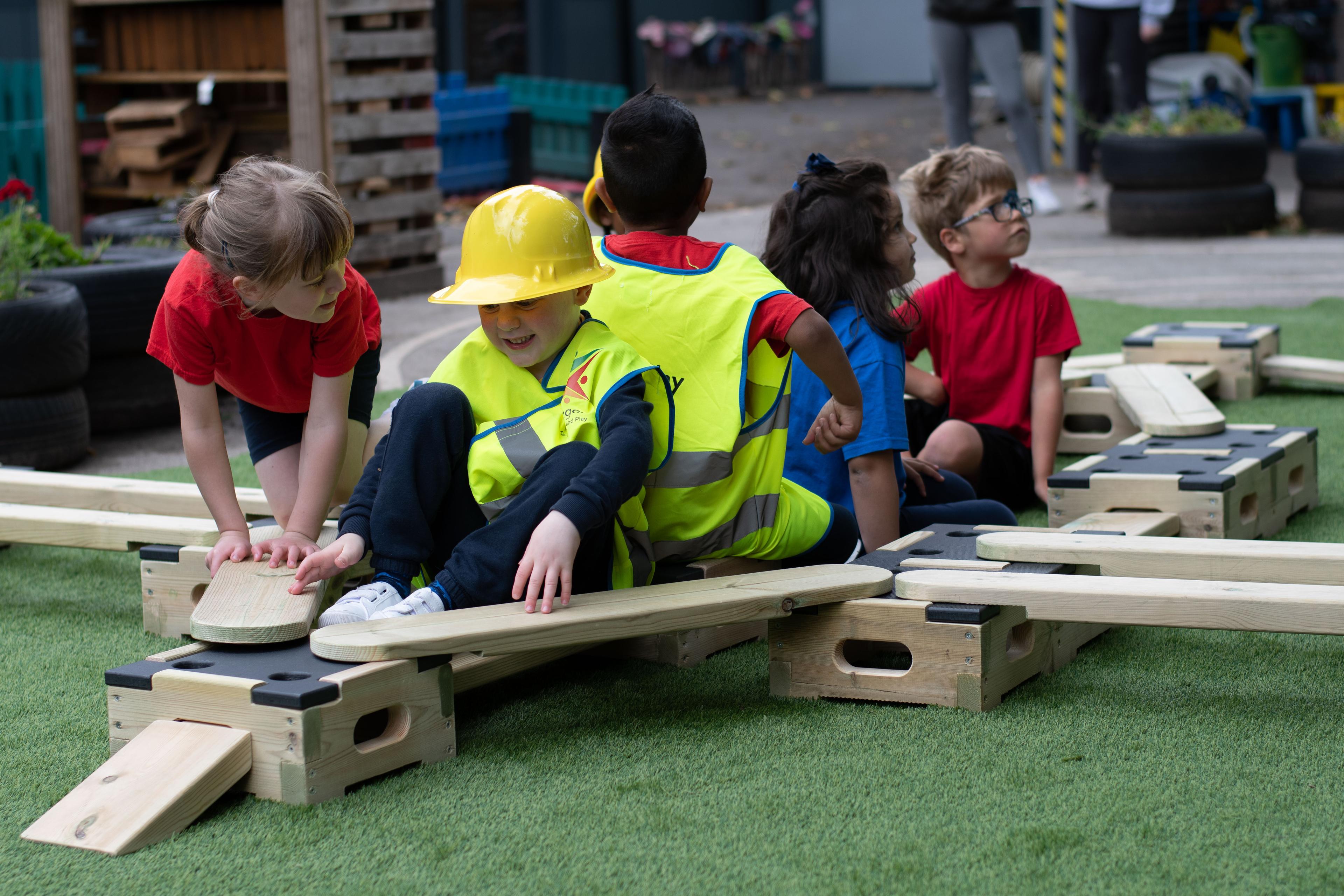 Children playing on the play builder, they are making a plane out of the blocks and planks