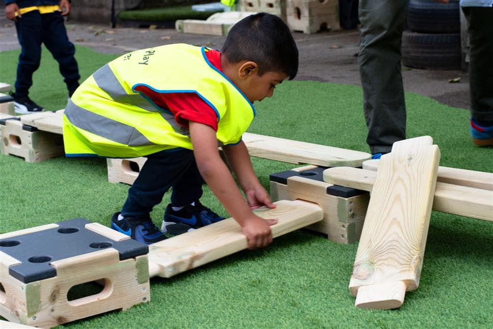 A young boy slotting the planks and blocks together