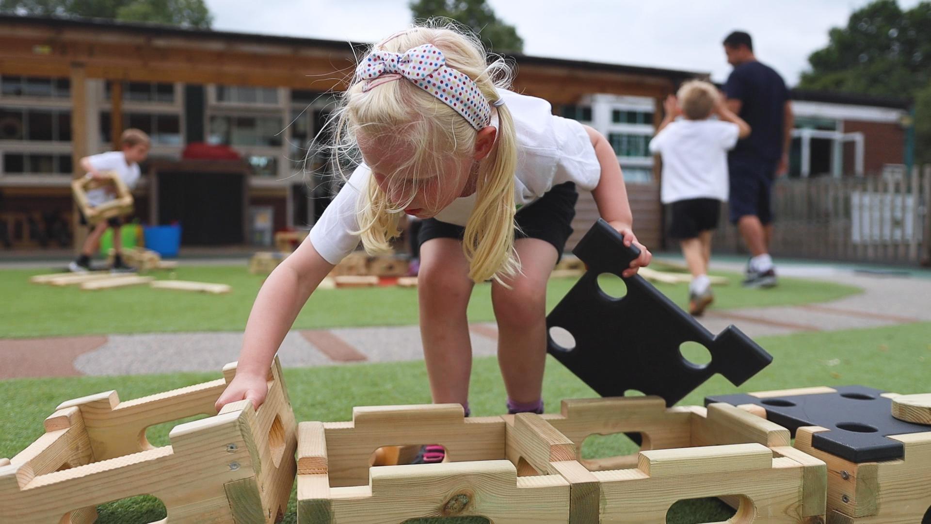 A young girl picking up the blocks