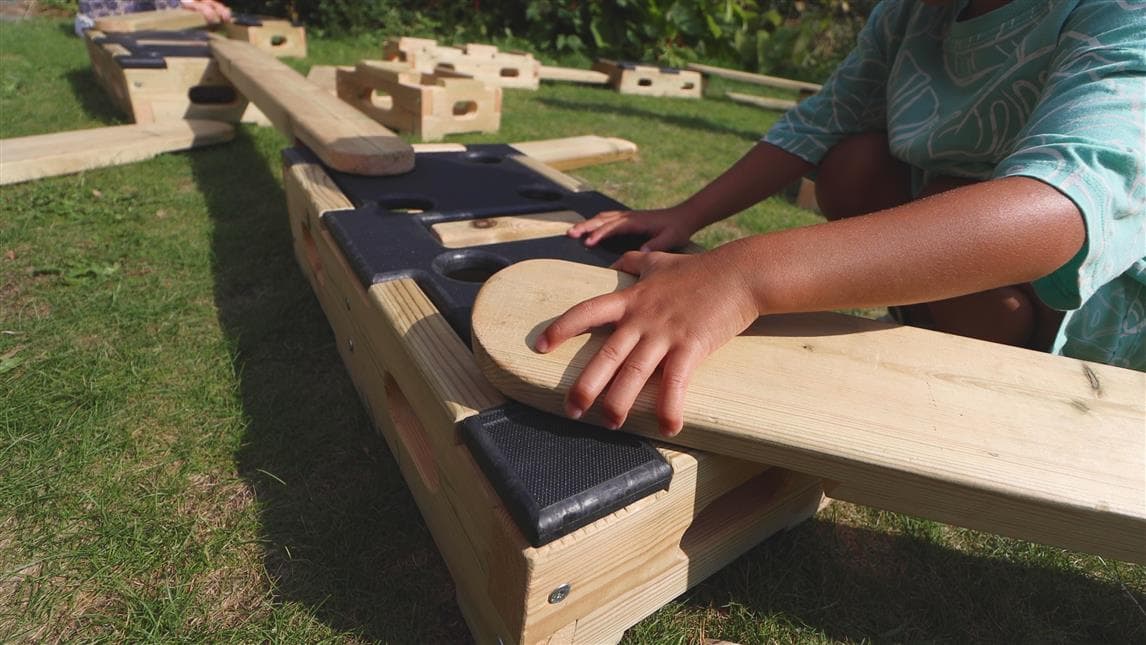 A young boy playing with the planks on the play builder