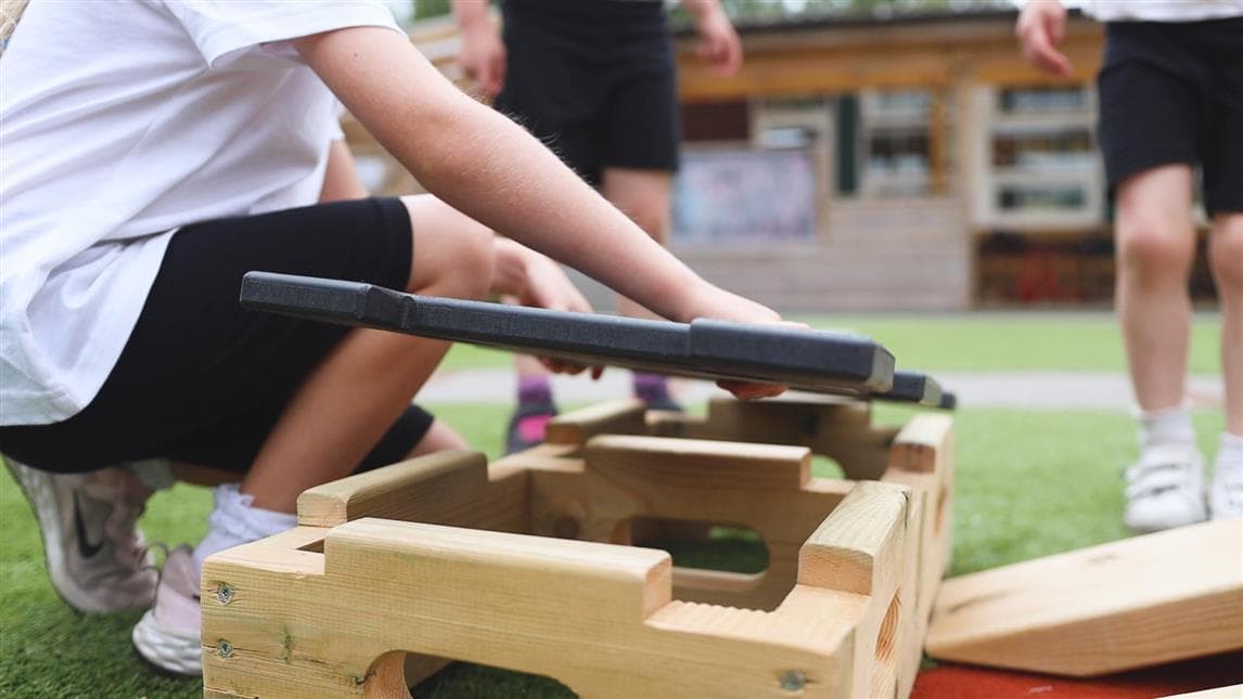 A young girl placing the lid of the play builder down onto the base