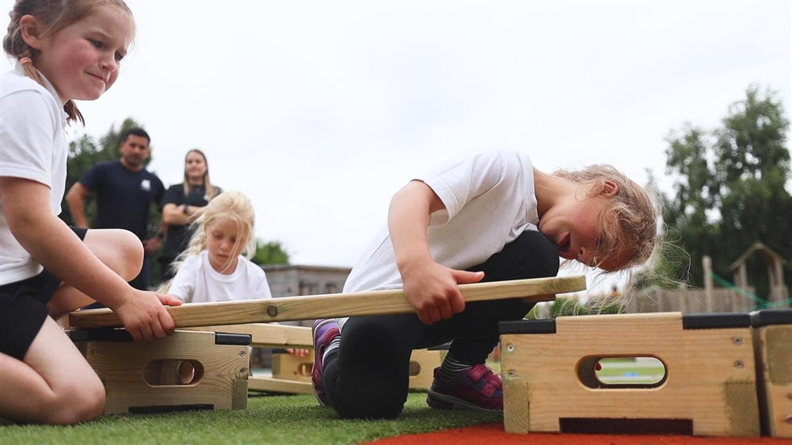 2 young children putting the plank on top of the play builder