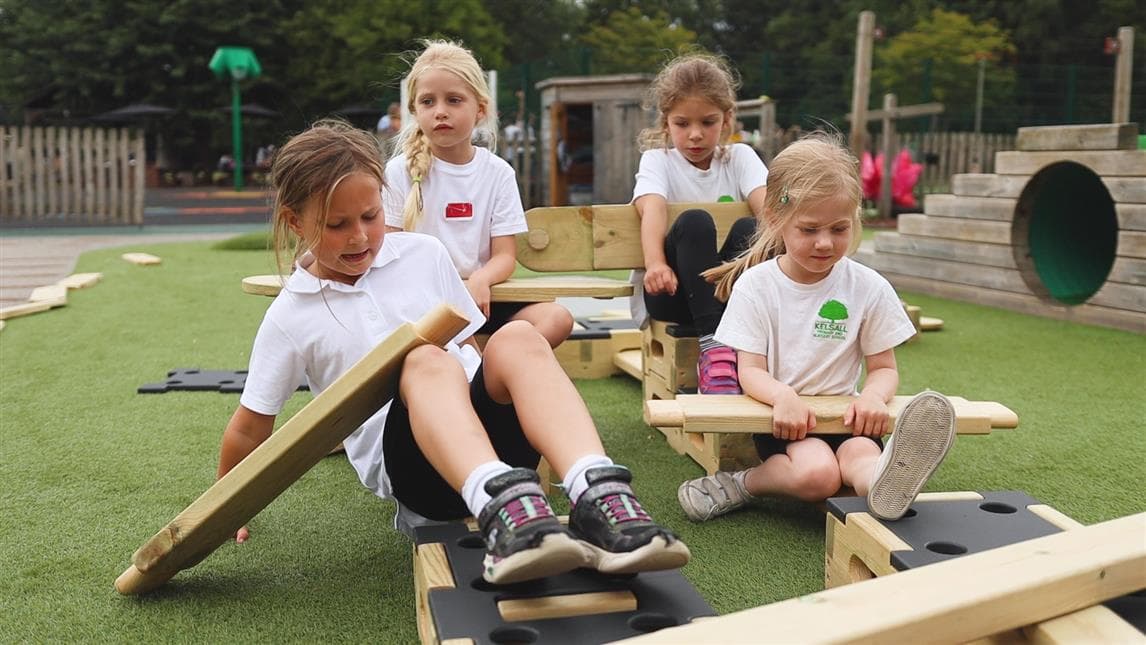 4 young girls playing with eh play builder pretending they are in a car