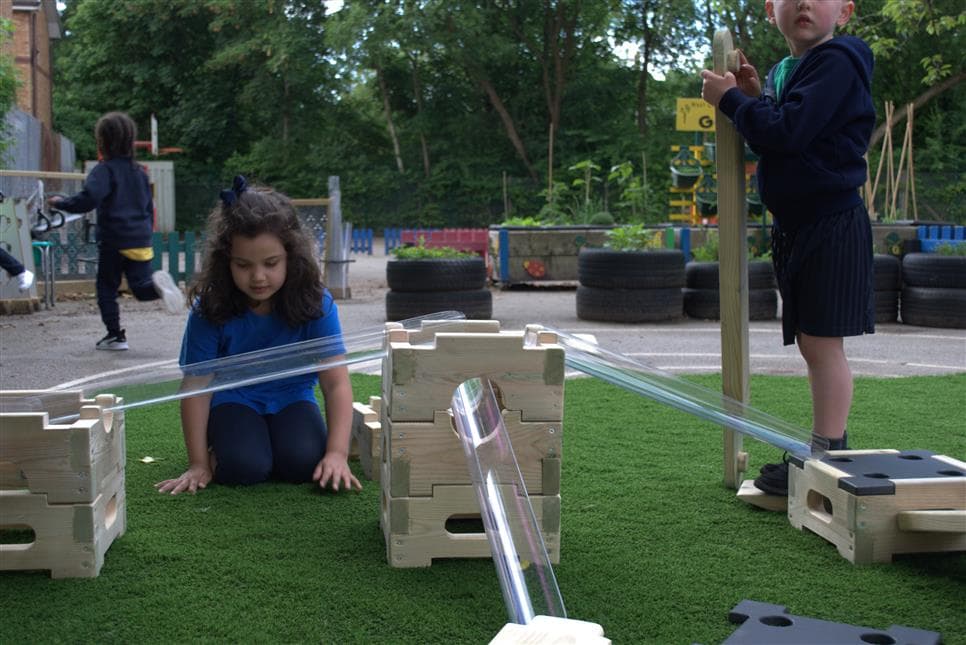 A young girl playing with the water channels on the play builder