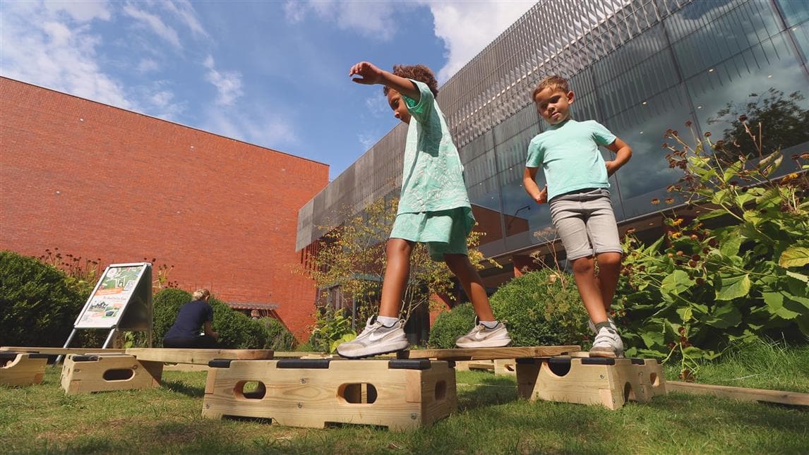 2 children walking across the play builder