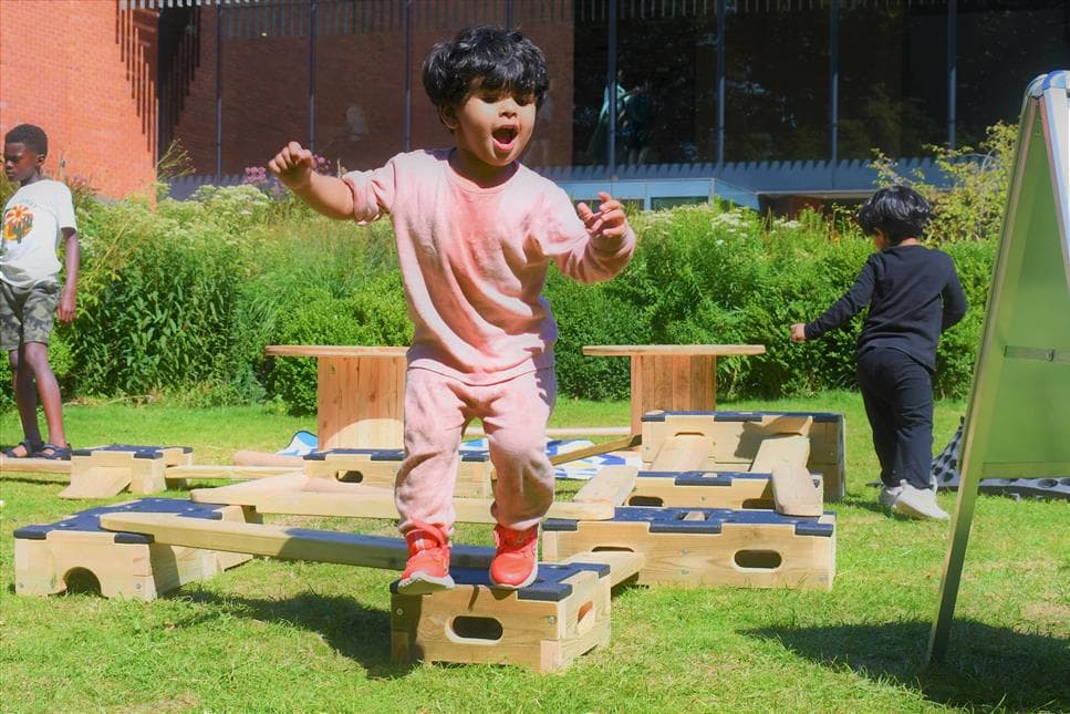 A young boy jumping off the end of the play builder