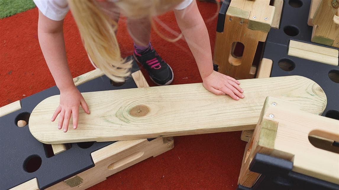 A young girl slotting the plank on top of the play builder