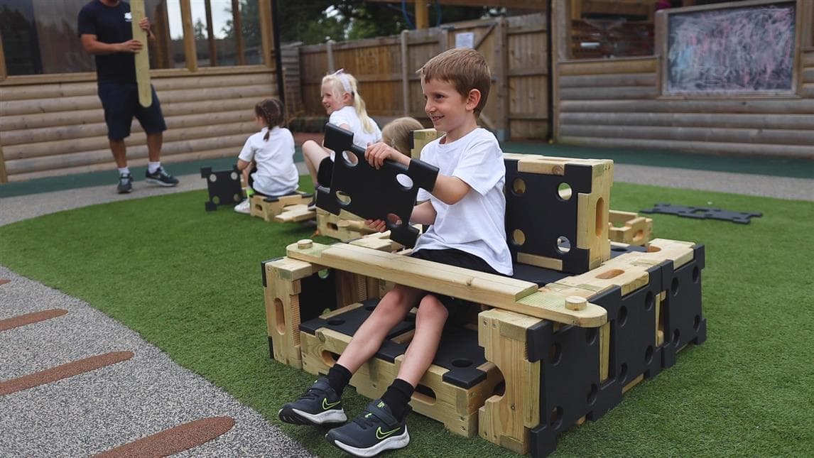 A young girl walking up the ramps on the play builder