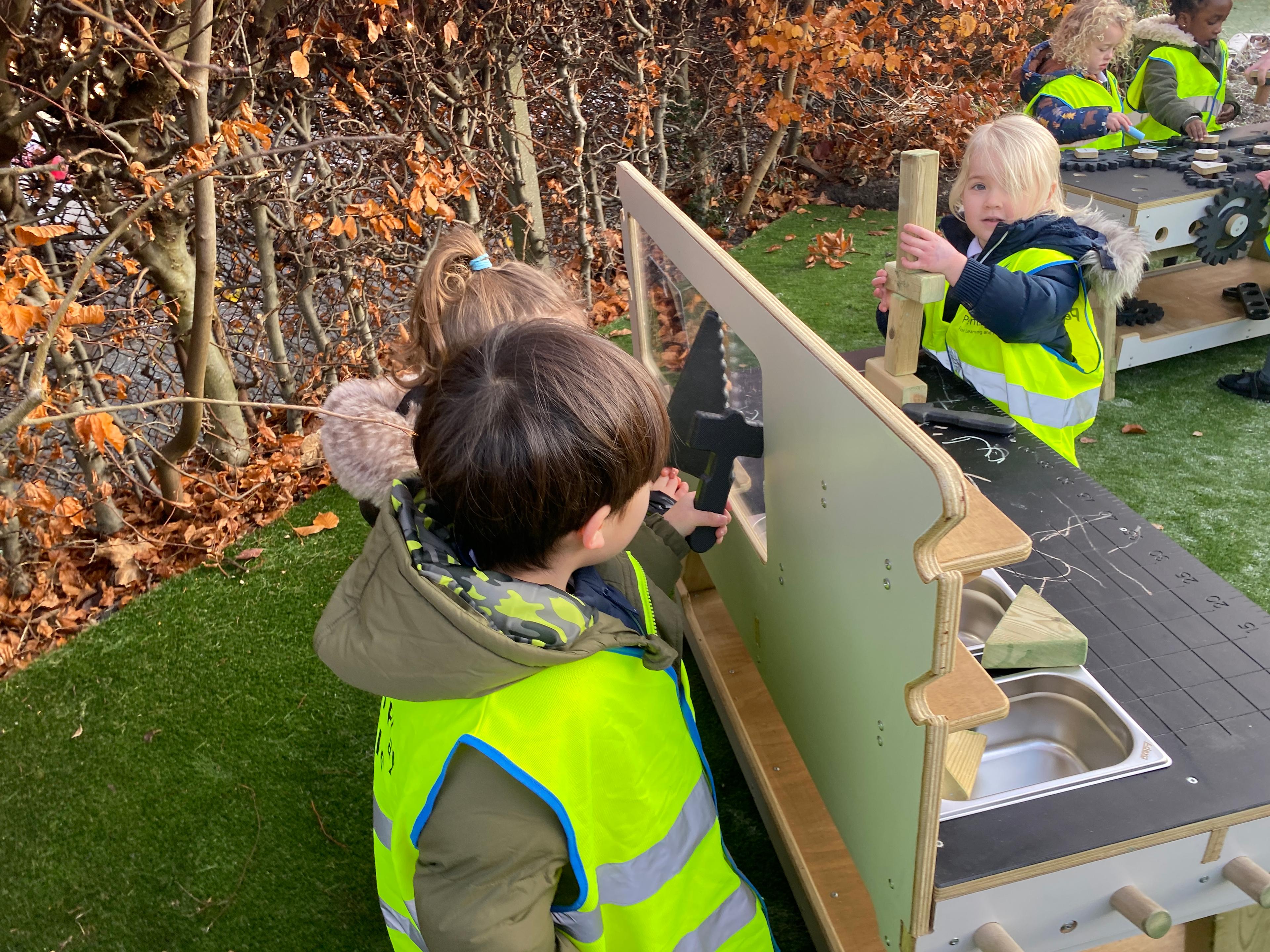 2 children using tools on the back of the construction table in their school
