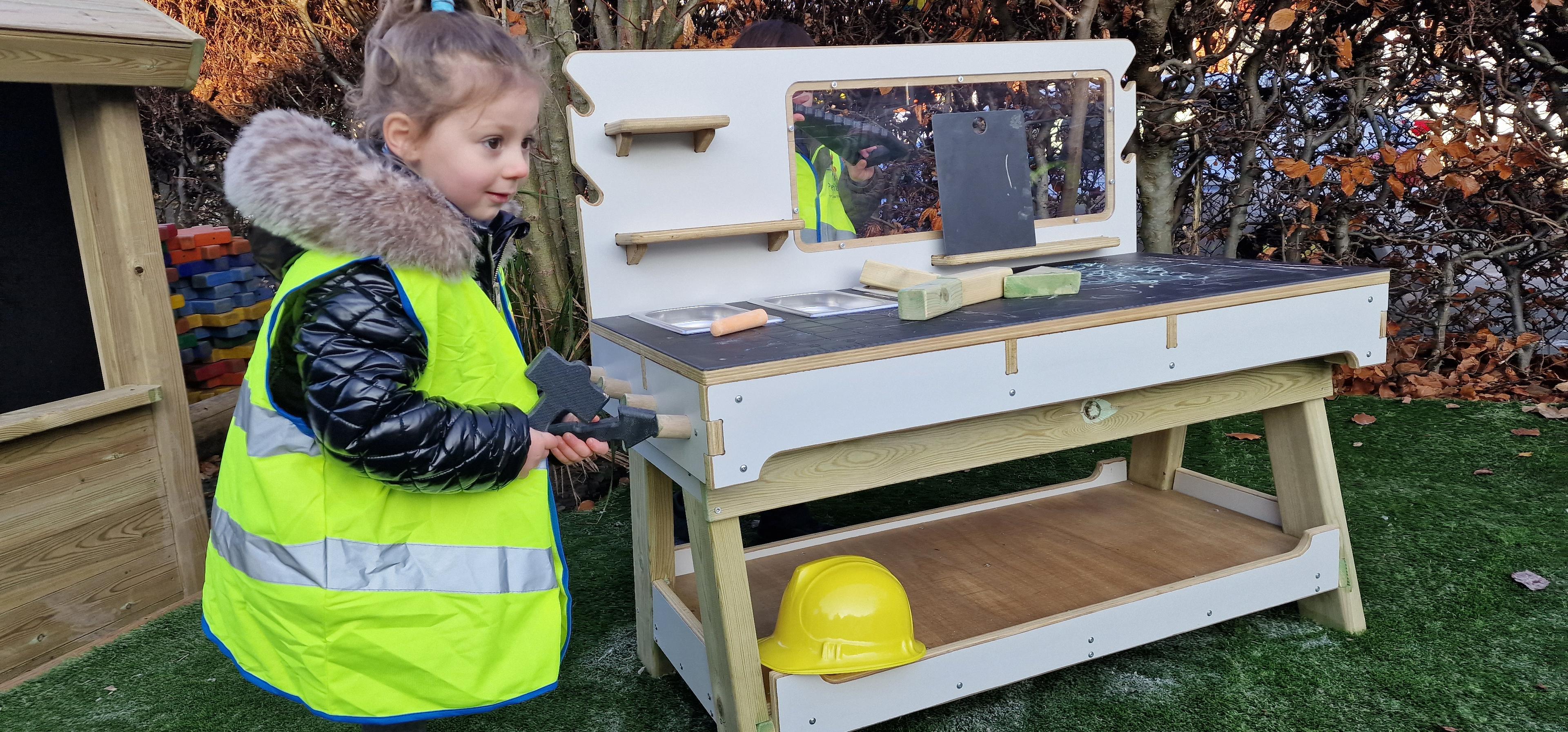 a young girl stood next to the construction table in the playground 
