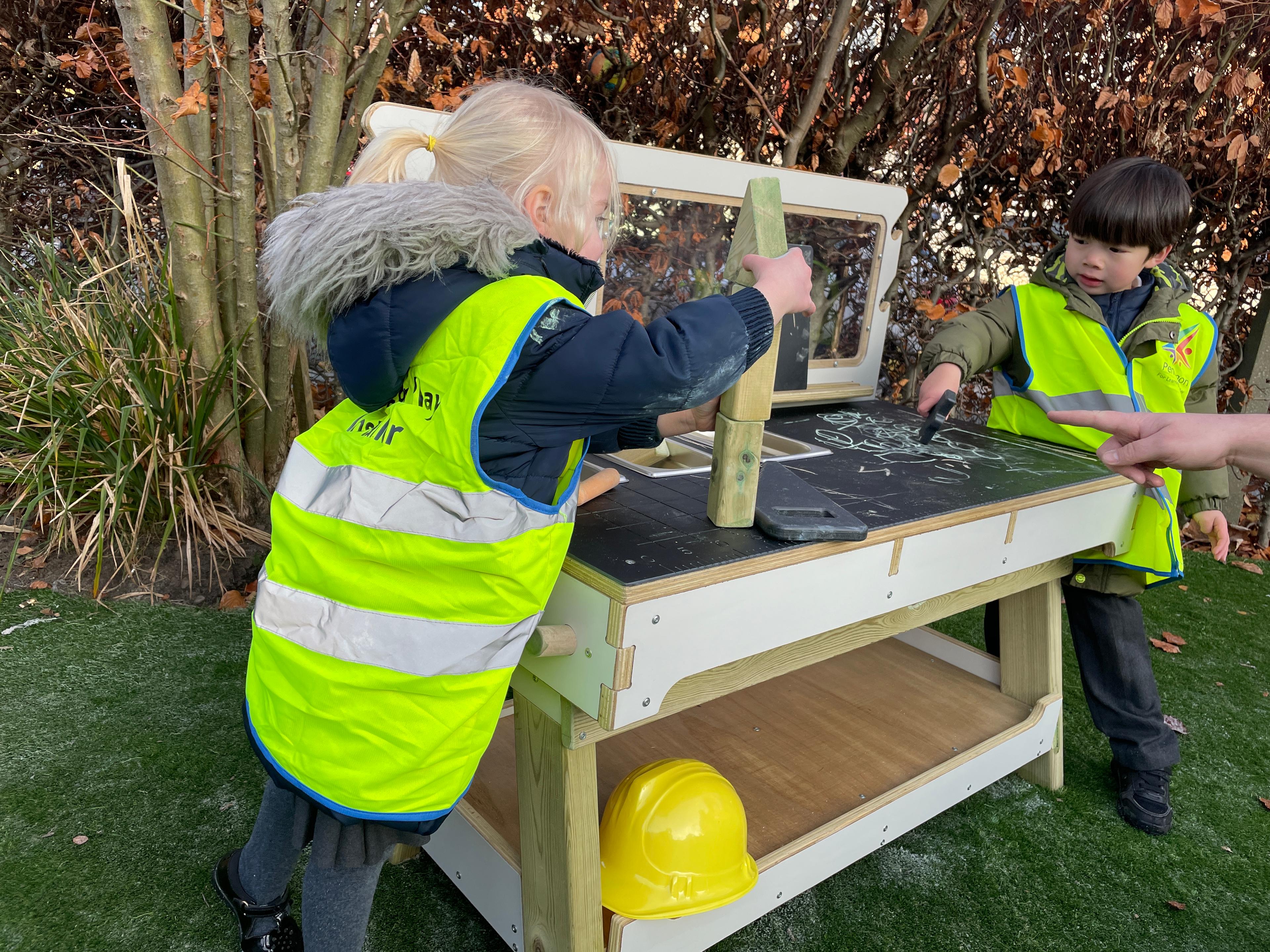 A young girl stacking blocks up on her construction bench