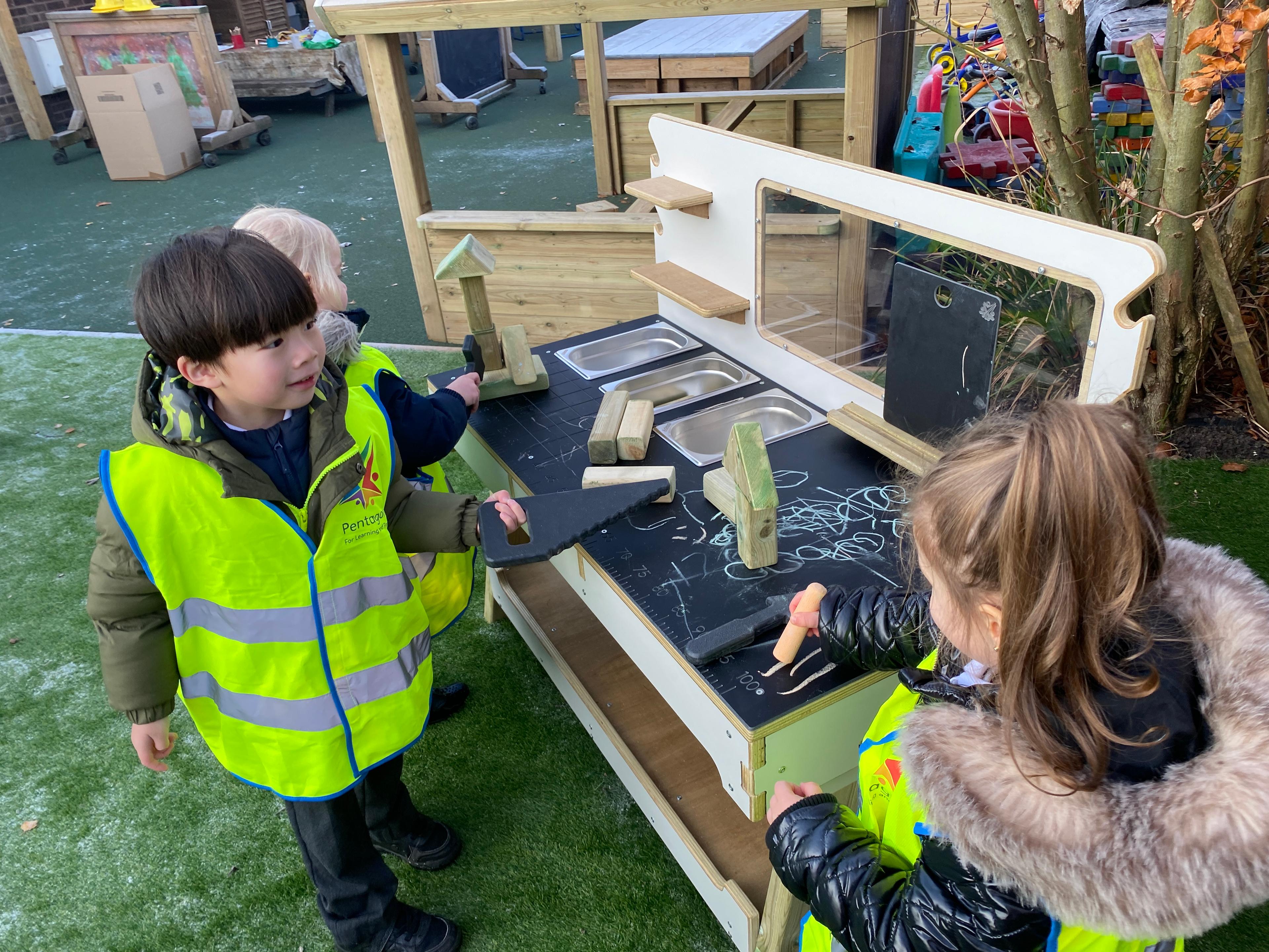 2 children playing with pretend construction toys