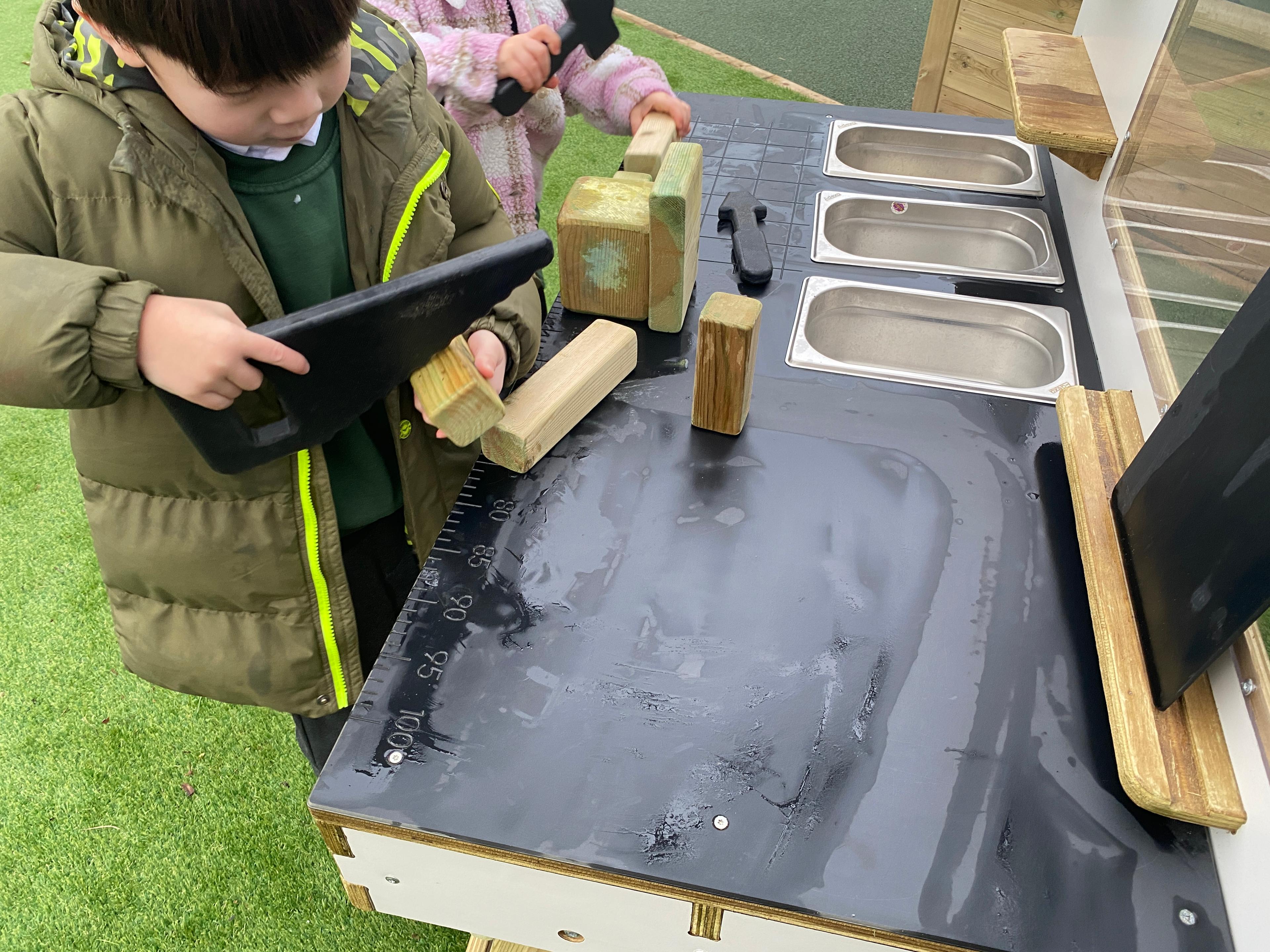 a young boy using a pretend saw to chop up wood on the construction table