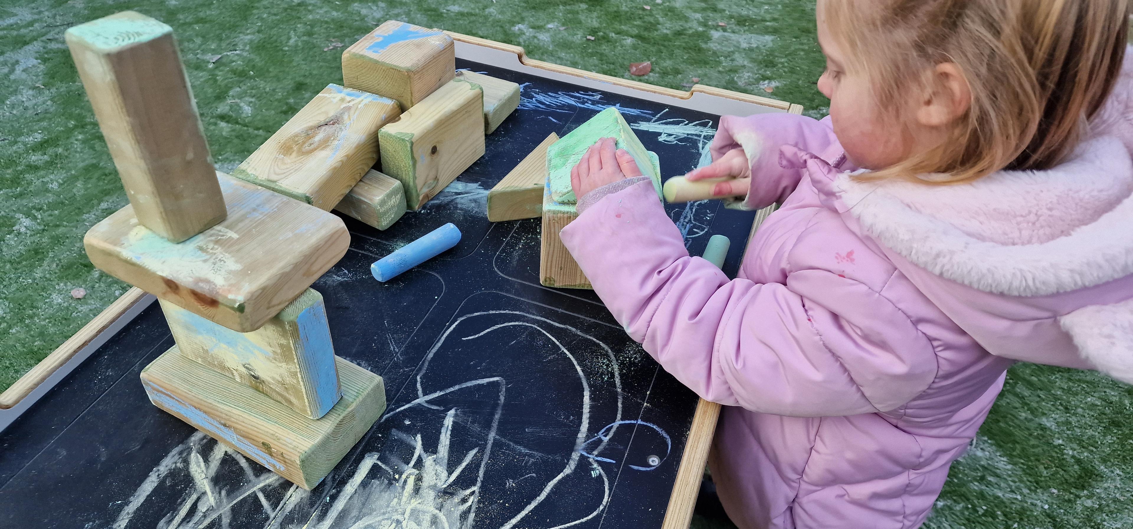A young girl playing on the construction workbench in her eyfs setting