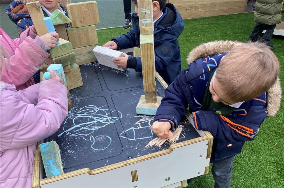 A young boy drawing with chalk on the workbench
