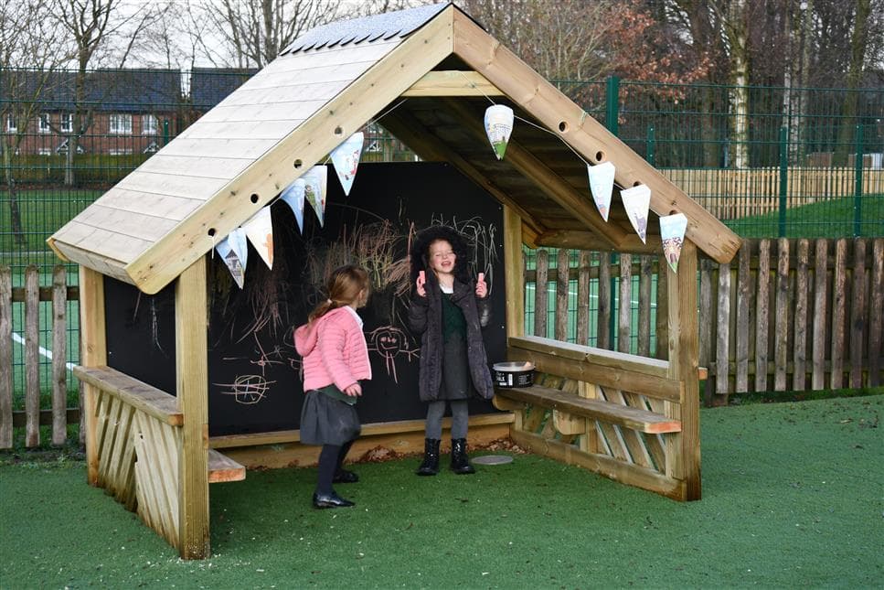 2 young girls playing in the giant playhouse in their playground